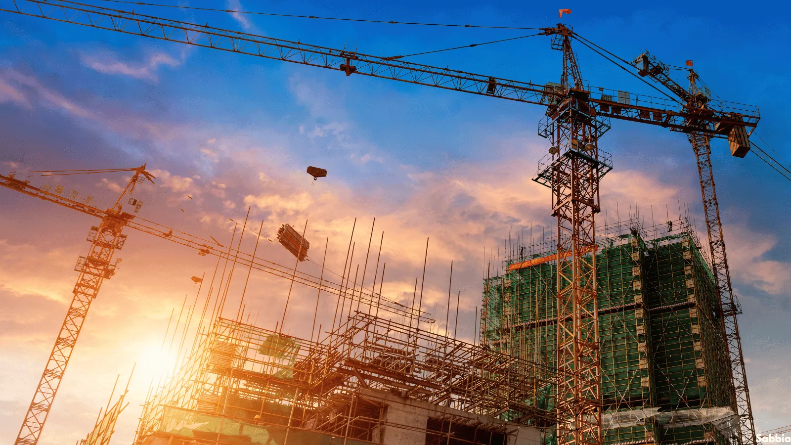 Tower cranes over a high-rise development under construction at sunset